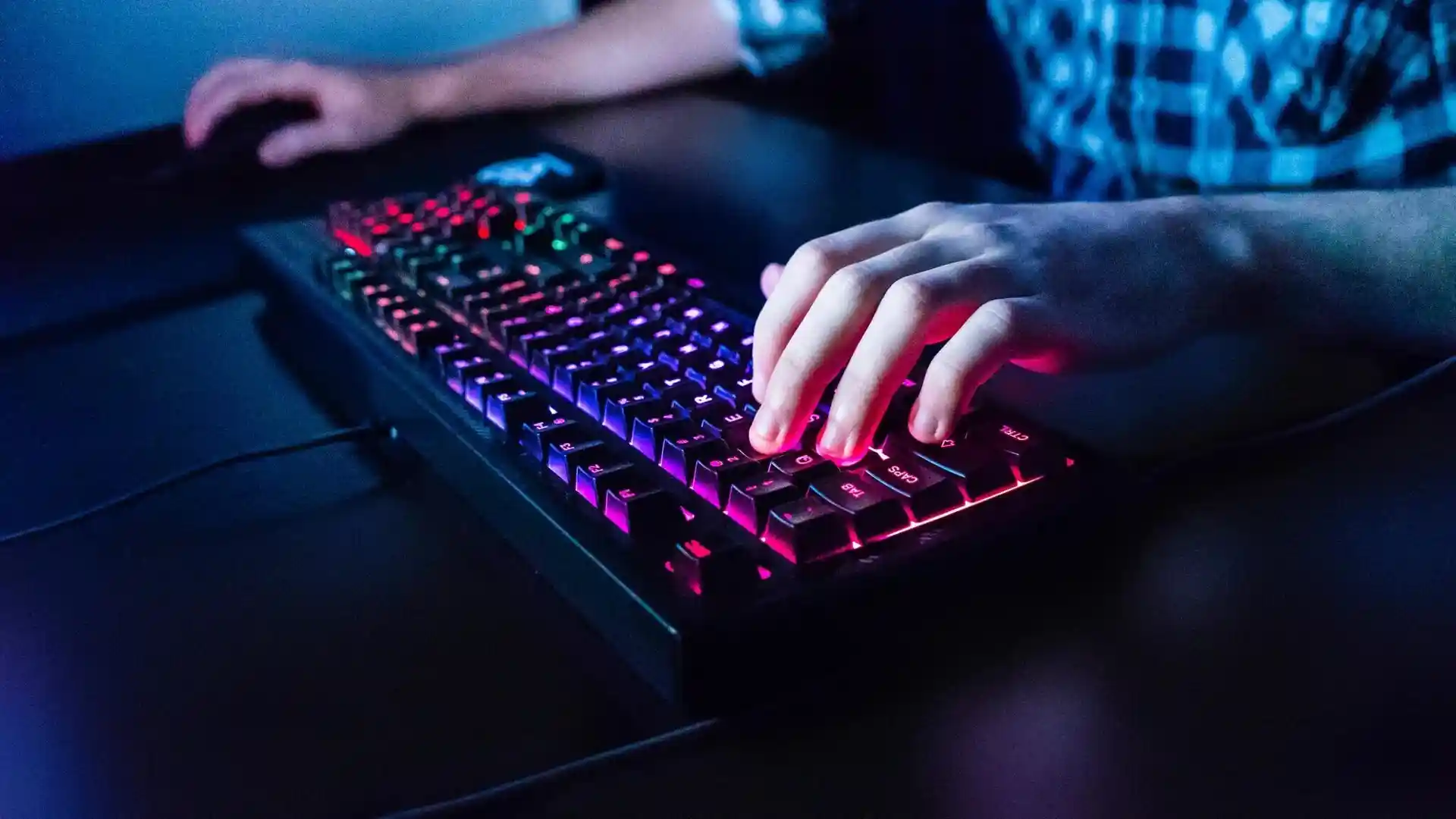 A person typing on a glowing mechanical keyboard.
